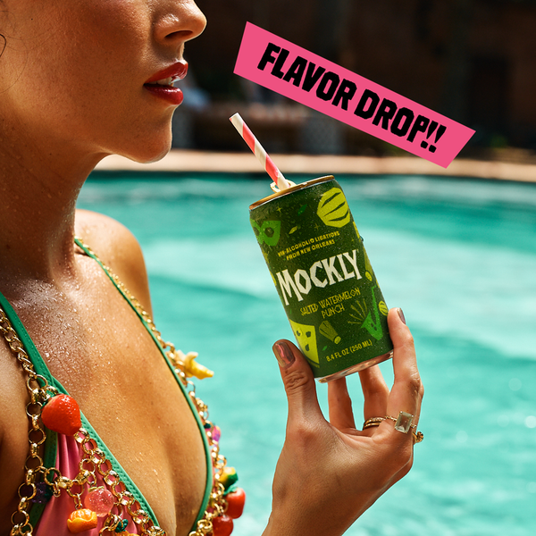 A woman in a pink and green swimsuit holds a can of Mockly Acidic Watermelon Poppy next to a swimming pool, with a pink graphic overlay that reads 'FLAVOR DROP!!'.